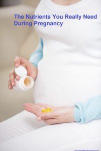 Close-up of pregnant woman sitting at sofa with vitamin pills in her hand.